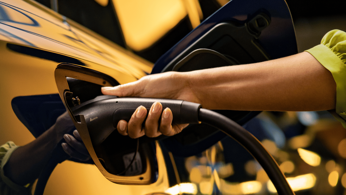 close up of hand grasping ev charger connector in yellow vehicle