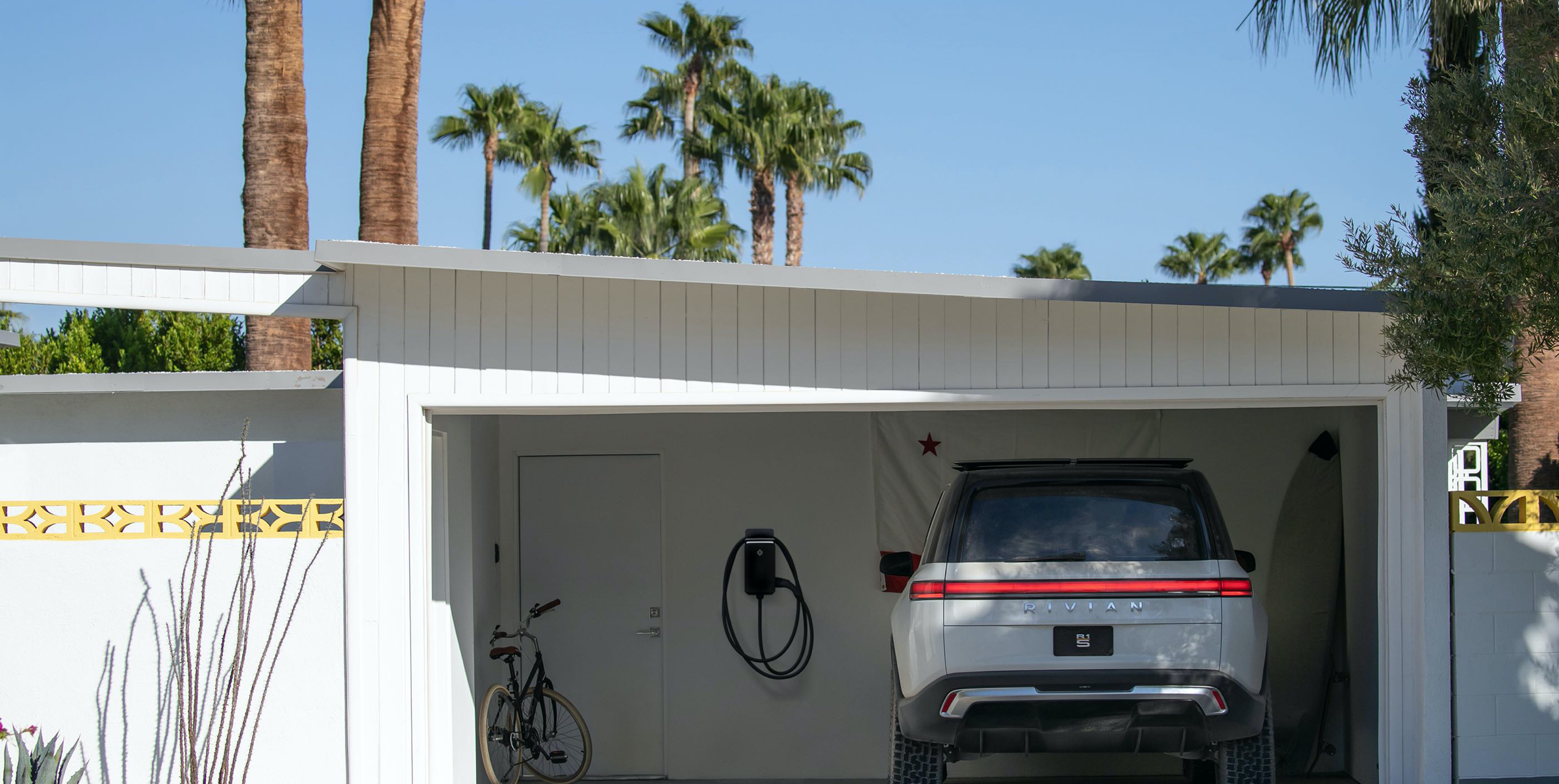 rivian ev charging panel in garage next to white vehicle