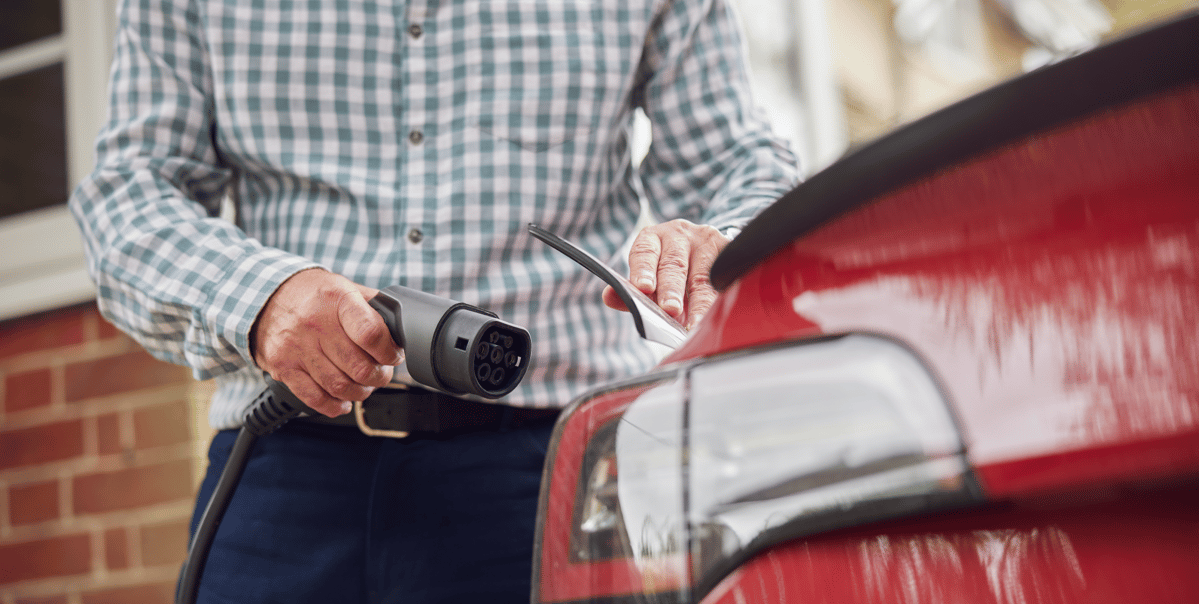 close up of man inserting ev charger connecter into vehicle