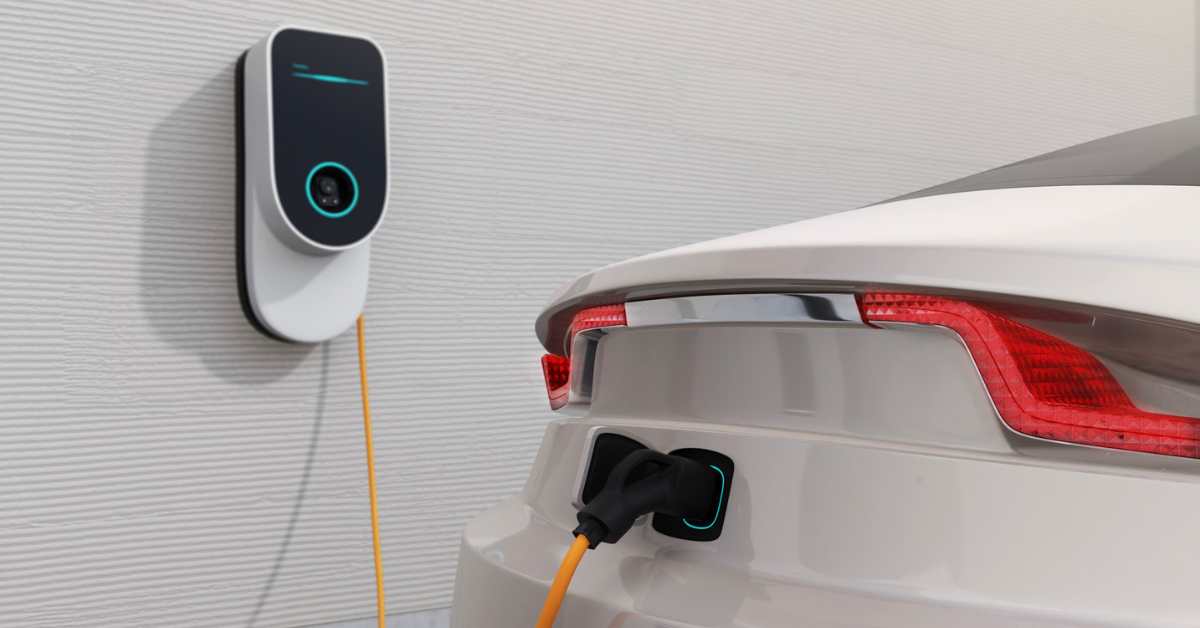 a white fleet electric vehicle is plugged into an at-home ev charging station demonstrating the convenience of overnight at home ev charging for fleet drivers.