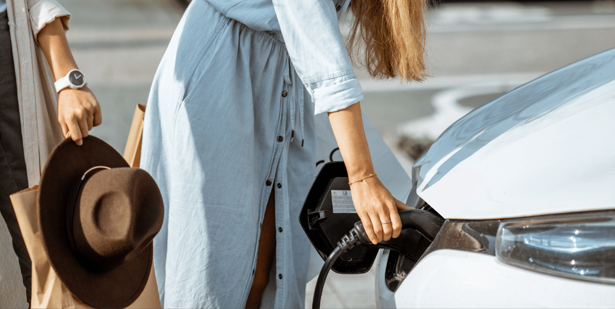 woman charging electric vehicle in commercial shopping center with ev charger