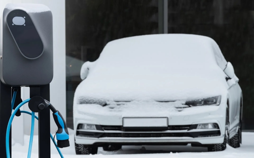 EV covered in snow by charging station