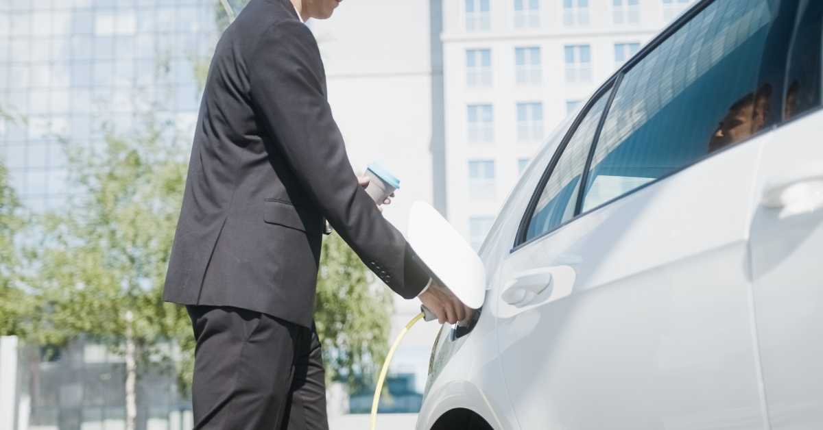 how fleet managers can stay ahead of the ever evolving automotive industry with electric vehicles. business man unplugs ev before beginning day.