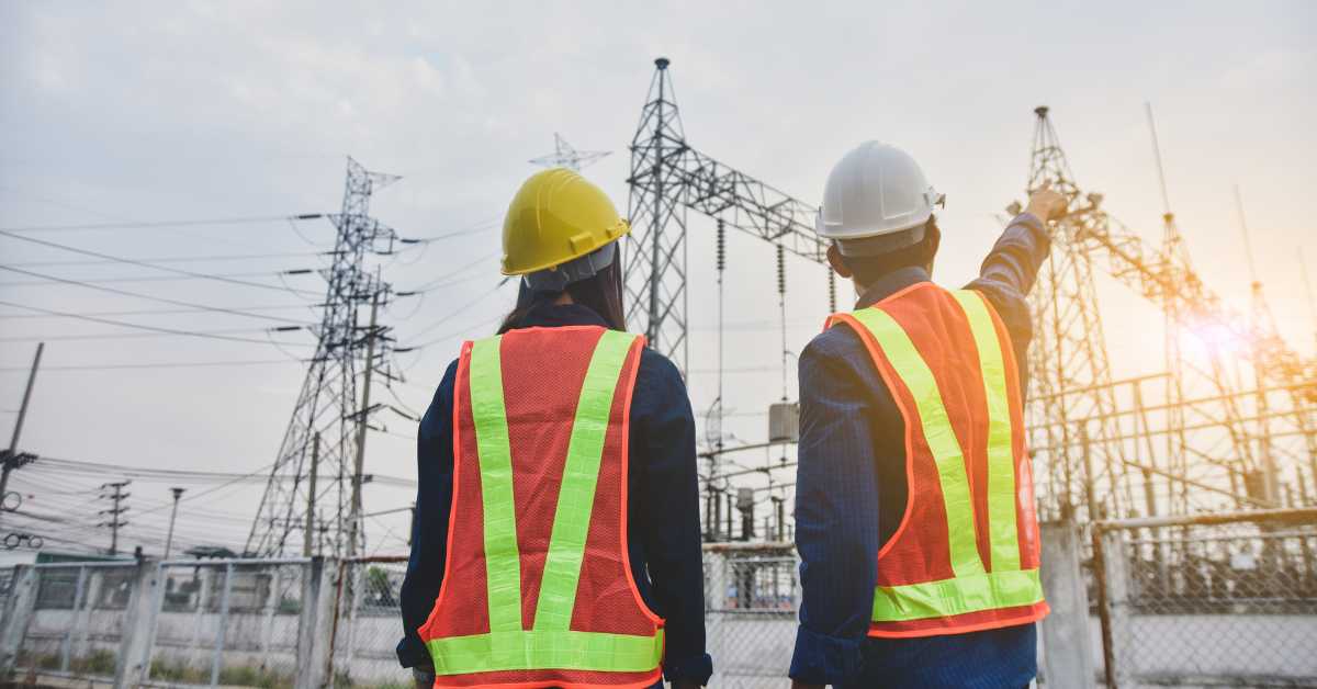 strides to strengthen the electrical grid depicted by two utility employees discussing electrification upgrades.