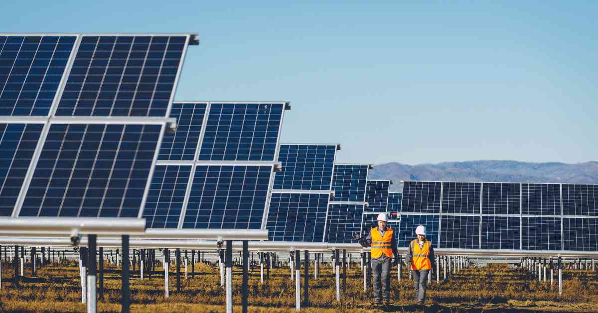 two electric utility employees walk through a solar power generation station, one of the sustainable measures that utilities can implement to further support the electric grid and EV charging infrastructure