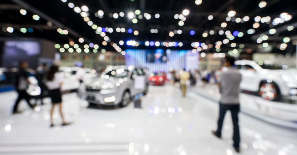 Vibrant autoshow floor bustling with attendees and showcasing the latest electric vehicles, reflecting the forward momentum of the auto industry in 2023 and its future trajectory.