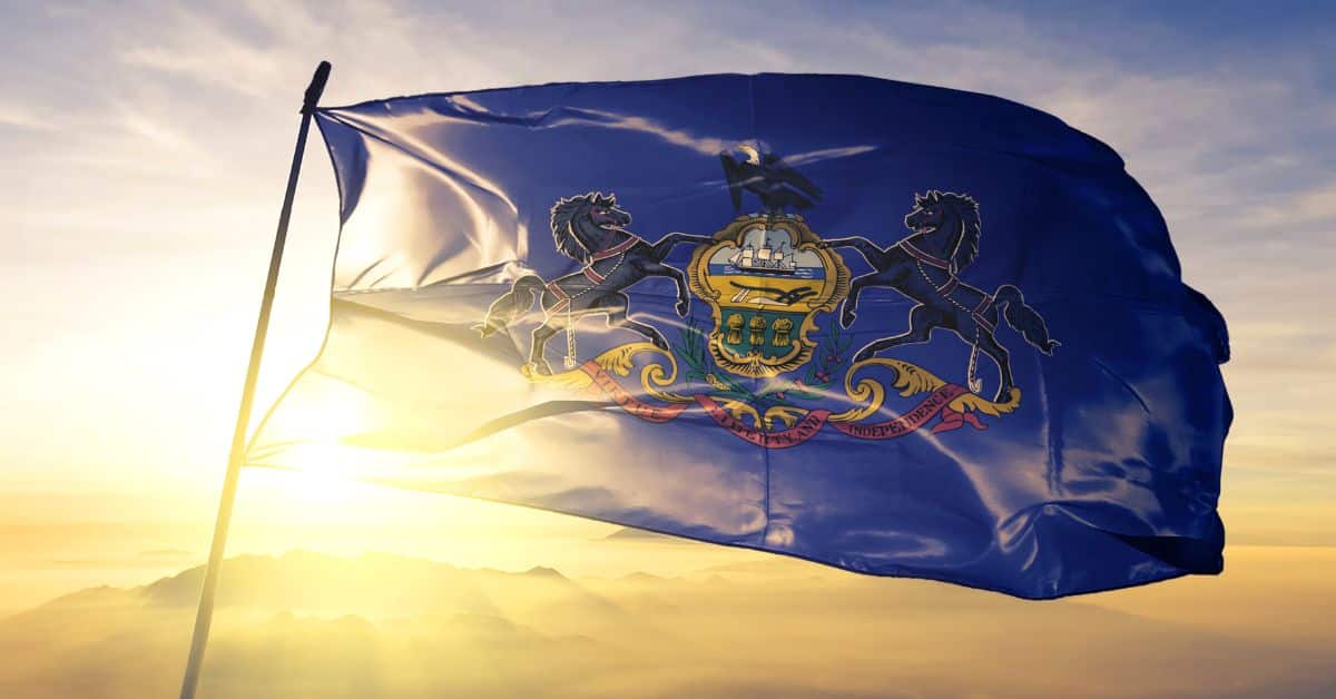 The Pennsylvania state flag gracefully waving atop a misty sunrise, symbolizing the rise and expansion of EV charging stations in Pennsylvania and the state's commitment to sustainable transportation