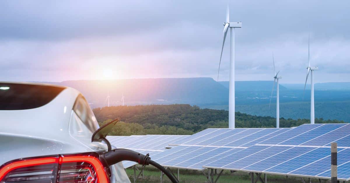 An electric vehicle plugged in and charging, with the backdrop of solar panels and wind turbines, showcasing the opportunities in the field for a renewable energy electrician