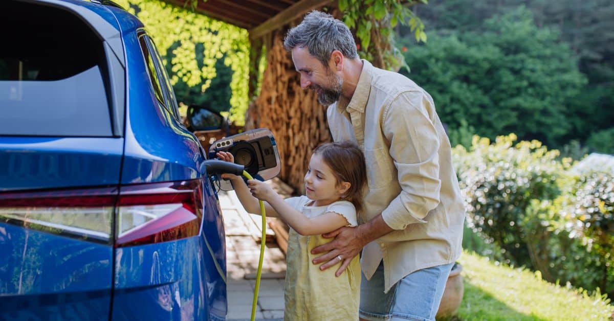 A joyful father and his little daughter charging their electric car together, prompting questions about the functioning of electric vehicle charging stations, emphasizing electrical compatibility and safety considerations