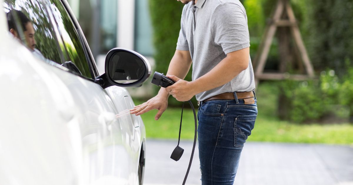 A man effortlessly powering up his electric vehicle at a home charging station, inviting exploration into the realm of the fastest EV charging station upgrades for your residence