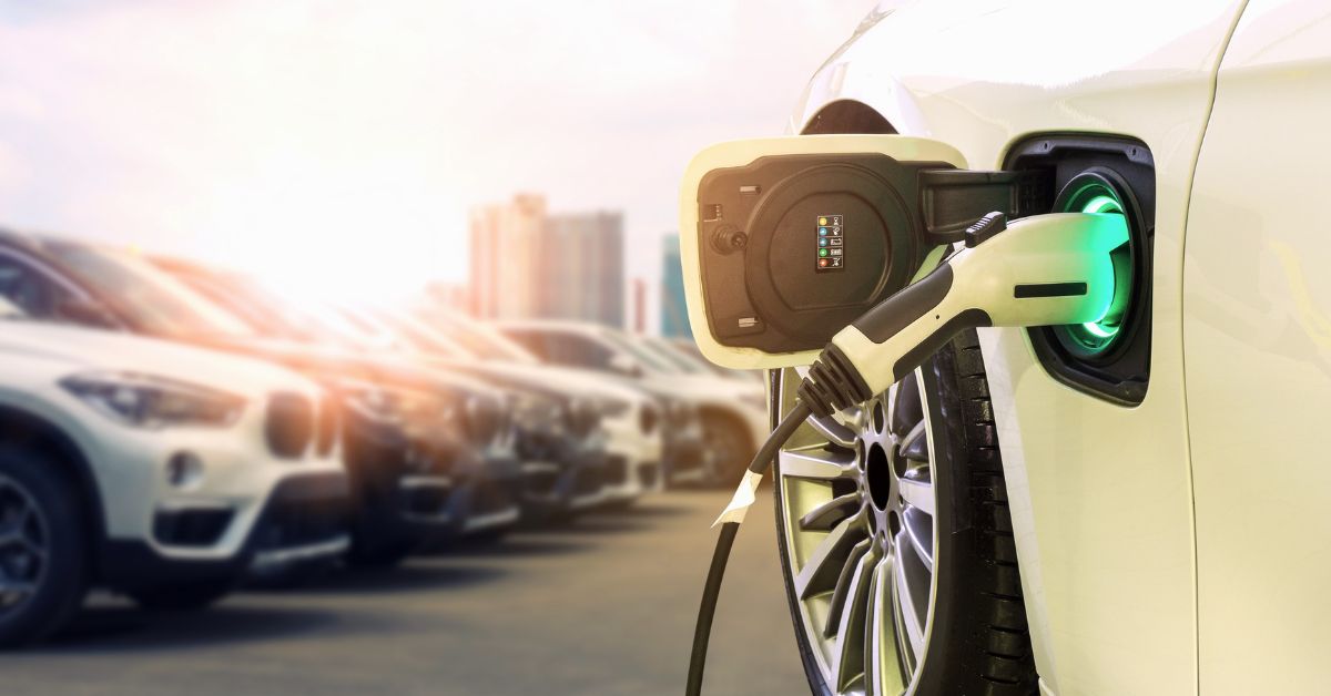 A power supply connected to an electric car for charging, emphasizing the shift towards electrification in transportation and its implications for the total cost of ownership, particularly from a fleet standpoint